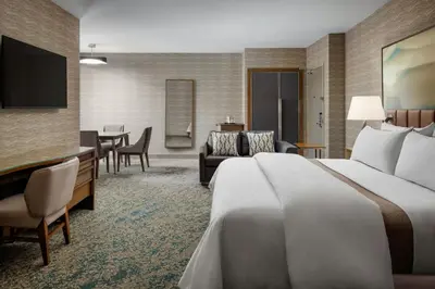 a hotel room with a bed and a dining room at The Westin Calgary Airport in Calgary