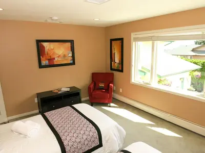 a bedroom with a bed and a chair and a window at A View of the Lake B & B in West Kelowna