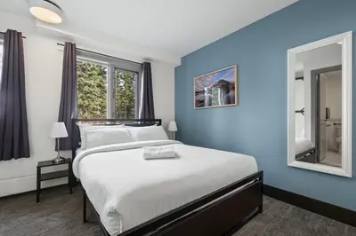 a blue bedroom with a bed and a mirror at HI Lake Louise Alpine Centre - Hostel in Lake Louise