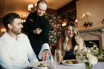 a man and a woman sitting at a table eating food at Oak Bay Beach Hotel in Victoria