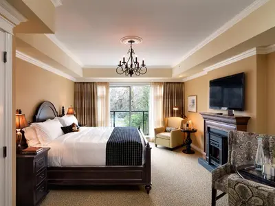 a bedroom with a bed and a television and a fireplace at Oak Bay Beach Hotel in Victoria
