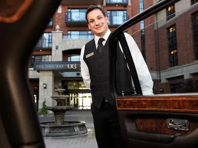 a man in a suit and tie standing next to a car at Oak Bay Beach Hotel in Victoria
