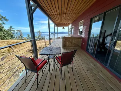 a patio with two chairs and a table on a deck at Shangri-La Oceanfront vacation home in Pender Island