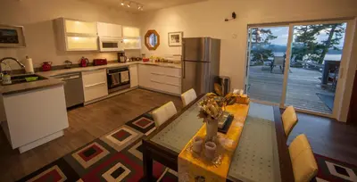 a large kitchen with a table and a refrigerator at Shangri-La Oceanfront vacation home in Pender Island