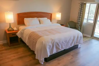 a bedroom with a large bed with two lamps and a chair at The Waterfront Suites and Marina in Nanaimo