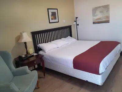 a bed in a room with a chair and a bed sidx sidx sidx at Travellers Motel in Cranbrook