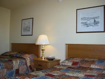 a hotel room with two beds and a lamp on a table at Discovery Inn in Yellowknife