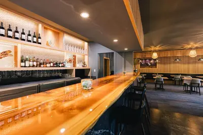 a bar with a long wooden counter in a restaurant at Kwa'lilas Hotel in Port Hardy