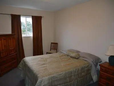 a bedroom with a bed and a dresser and a window at North Coast Trail Backpackers Ltd in Port Hardy