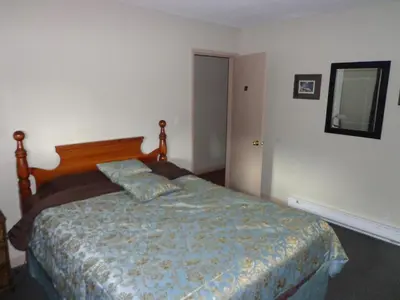 a bedroom with a bed with a wooden headboard and a mirror at North Coast Trail Backpackers Ltd in Port Hardy