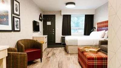 a hotel room with a bed and a chair at Mountaineer Lodge in Lake Louise
