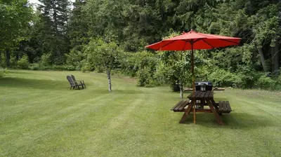 a picnic table with an umbrella and two chairs at The Inn at the Ninth Hole Bed & Breakfast in Salmon Arm