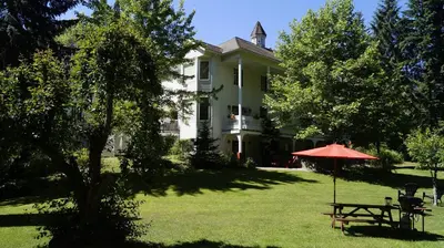 a house with a table and an umbrella in the yard at The Inn at the Ninth Hole Bed & Breakfast in Salmon Arm