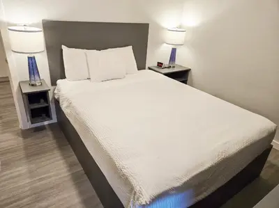 a bedroom with a white bed with two night stands at Motel 6 Merritt, BC in Merritt