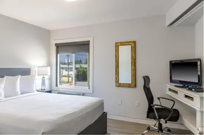 a bedroom with a bed and a tv and a chair at Motel 6 Merritt, BC in Merritt