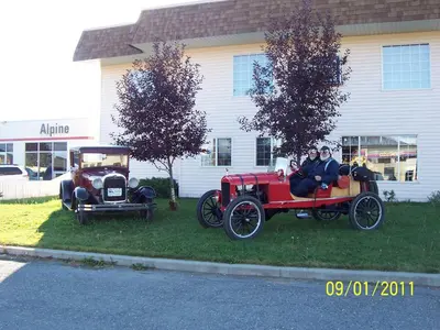 two people riding in an old car on the grass at Model A Inn in Cranbrook