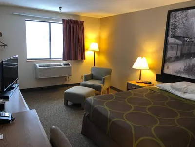 a hotel room with a bed and a chair and a television at Super 8 by Wyndham Salmon Arm in Salmon Arm