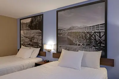 two beds in a hotel room with a picture on the wall at Super 8 by Wyndham Kamloops On The Hill in Kamloops