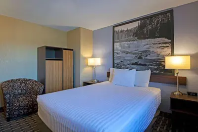 a hotel room with a large bed and a chair at Super 8 by Wyndham Kamloops On The Hill in Kamloops
