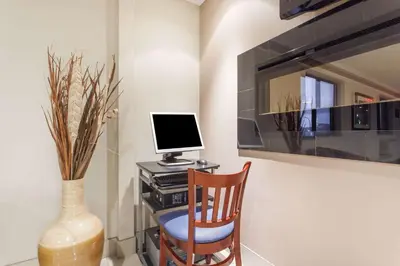 a desk with a computer and a chair and a vase at Super 8 by Wyndham Kamloops On The Hill in Kamloops
