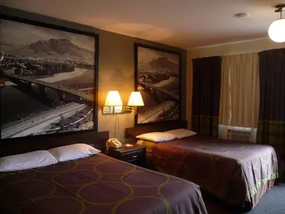 a hotel room with two beds and pictures on the wall at Super 8 by Wyndham Kamloops East in Kamloops