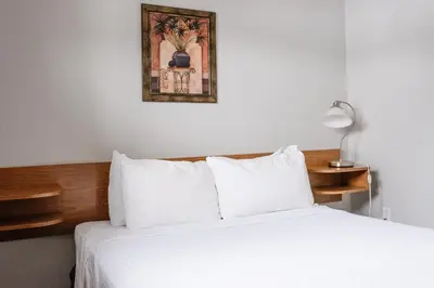 a bedroom with a white bed and a picture on the wall at Paradise Motel in Sicamous