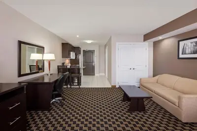 a living room with a couch and a desk at Ramada by Wyndham Cold Lake in Cold Lake