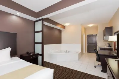 a hotel room with a bed and a bath tub at Ramada by Wyndham Cold Lake in Cold Lake