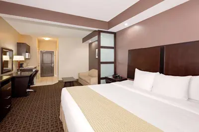 a hotel room with a large bed and a bathroom at Ramada by Wyndham Cold Lake in Cold Lake