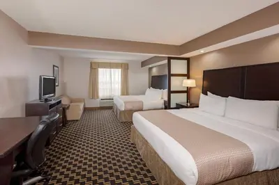 a hotel room with two beds and a flat screen tv at Ramada by Wyndham Cold Lake in Cold Lake