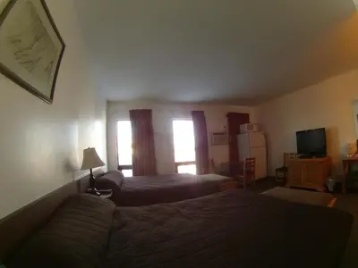 a hotel room with two beds and a television at Rycroft Hotel in Rycroft