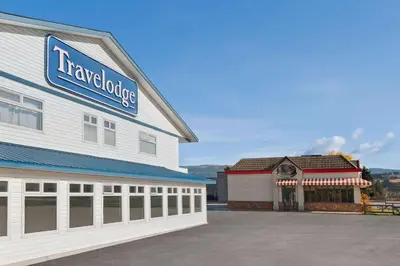 a large white building with a car dealership at Travelodge by Wyndham Salmon Arm BC in Salmon Arm