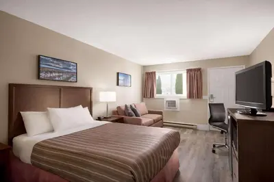 a hotel room with a bed and a flat screen tv at Travelodge by Wyndham Salmon Arm BC in Salmon Arm