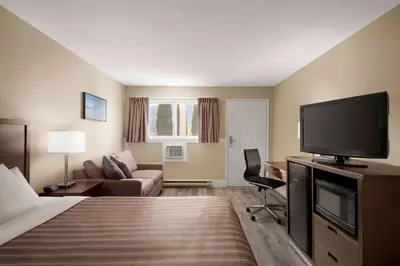 a hotel room with a bed and a flat screen tv at Travelodge by Wyndham Salmon Arm BC in Salmon Arm