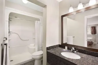 a bathroom with a sink and a toilet and a mirror at Travelodge by Wyndham Salmon Arm BC in Salmon Arm
