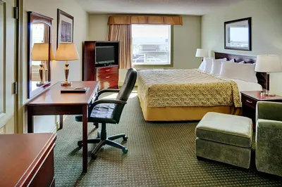 a hotel room with a bed and a desk and a chair at Nova Inn Acheson in Spruce Grove