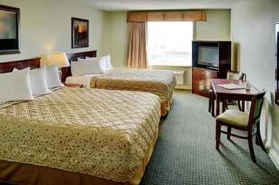 a hotel room with two beds and a television at Nova Inn Acheson in Spruce Grove