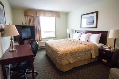 a hotel room with a bed and a desk and a television at Nova Inn Acheson in Spruce Grove