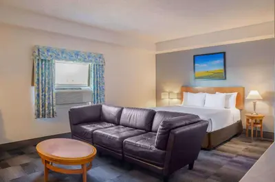 a hotel room with a couch and a bed at Days Inn & Conference Centre by Wyndham Camrose Norsemen in Camrose