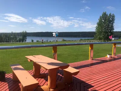 a wooden bench on a deck with a view of the water at Cariboo Log Guest House in Lac La Hache