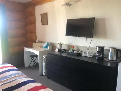 a bedroom with a dresser with a television on the wall at Cariboo Log Guest House in Lac La Hache