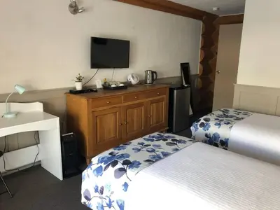 a hotel room with two beds and a flat screen tv at Cariboo Log Guest House in Lac La Hache