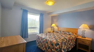 a hotel room with a bed and a window at Misty Mountain Inn & Suites in Grande Cache