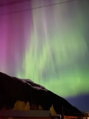 an aurora in the sky over a mountain at Bear Valley Guesthouse in Stewart