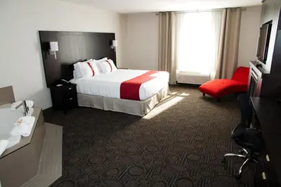 a hotel room with a bed and a red chair at Holiday Inn Hotel & Suites Red Deer by IHG in Red Deer