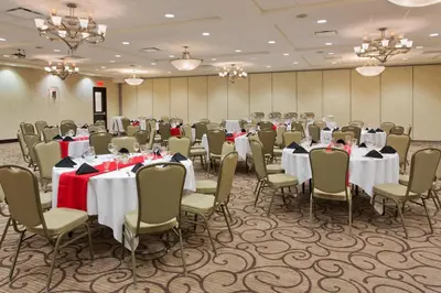 a conference room with tables and chairs with red napkins at Holiday Inn Hotel & Suites Red Deer by IHG in Red Deer