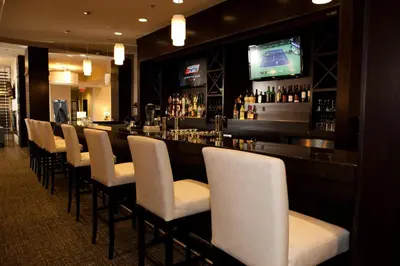 a bar with a row of white chairs and a television at Holiday Inn Hotel & Suites Red Deer by IHG in Red Deer