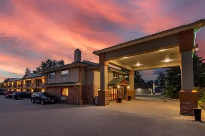 a building with cars parked in a parking lot at SureStay Plus Hotel by Best Western Salmon Arm in Salmon Arm