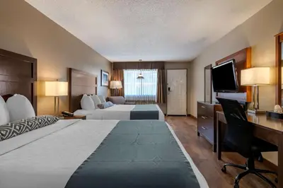 a hotel room with two beds and a desk and a television at SureStay Plus Hotel by Best Western Salmon Arm in Salmon Arm