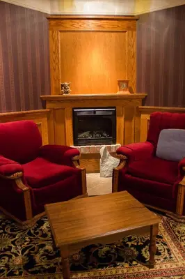 a living room with red chairs and a fireplace at Genelle House B&B Guest House in Genelle